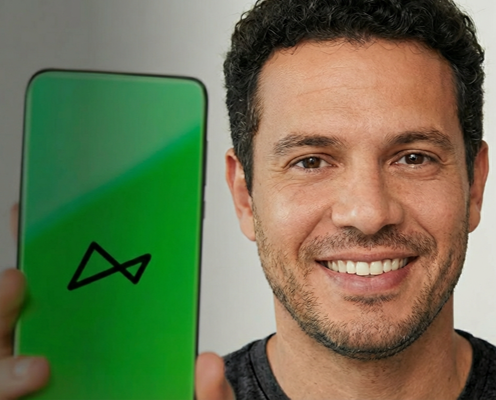 Uma mulher de cabelos escuros na altura do pescoço sorri enquanto olha para o seu smartphone. Ela está do lado de fora de casa usando um vestido preto com detalhes brancos.